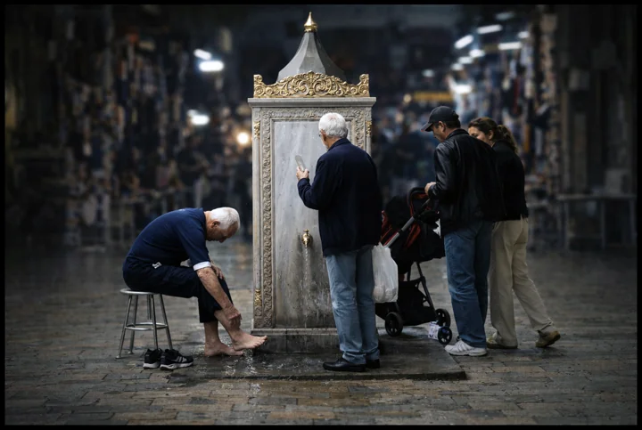 People gathered beside an illuminated fountain