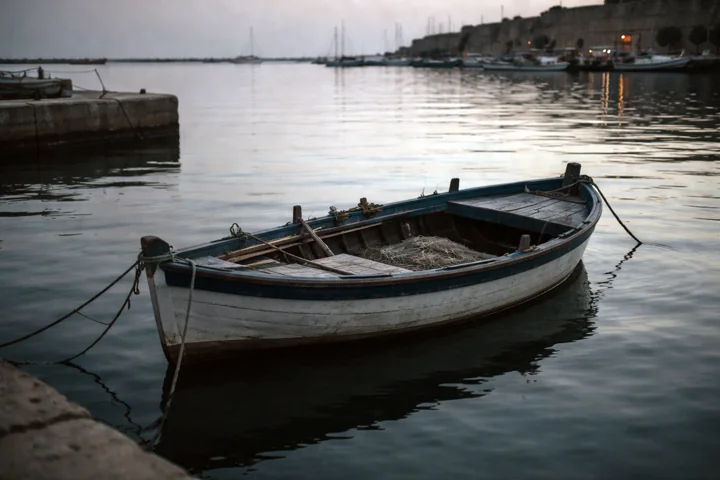 A small wooden boat moored in calm harbour water