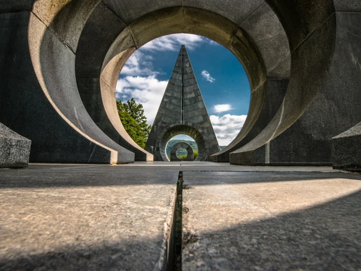 A pointed monument framed by circular openings in a concrete structure